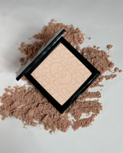 Rozświetlacz LUMIÉR Locco nałożony na kości policzkowe i dekolt – subtelny blask i podkreślona opalenizna